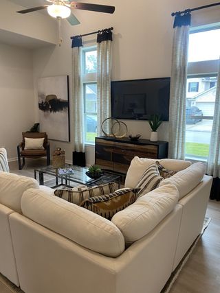 A cozy living room with plush white sofas, abstract art, and large windows offering natural light.