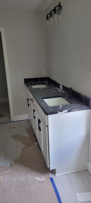 A sleek double vanity with a black countertop, modern fixtures, and soft lighting illuminates this stylish bathroom space.