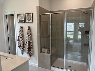 A modern bathroom featuring a glass-enclosed shower, sleek tiles, and elegant wall art for a sophisticated look.