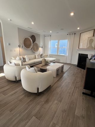 Model Home Modern living room with cozy seating, stylish decor, and a fireplace, featuring neutral tones and wood flooring.