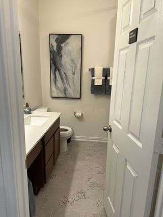 A contemporary bathroom features abstract art, sleek vanity, and tiled floors.