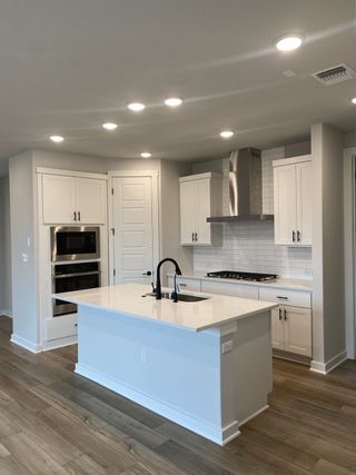 Model Home A sleek kitchen with white cabinetry, a modern island, recessed lighting, and stainless steel appliances.