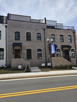 Classic brick townhomes with black accents and rooftop terraces in Skyview On Broad by Kittle Homes (Sugar Hill, GA).