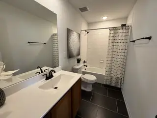 A modern bathroom with sleek black fixtures, white tiles, a spacious vanity, and stylish decor accents.