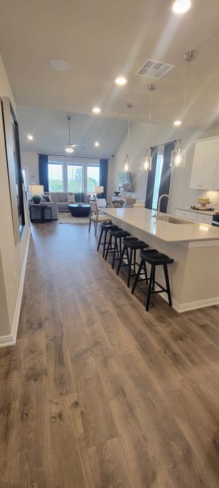 Model Home A modern kitchen with sleek counters, pendant lighting, and an open layout leading to a cozy living area.