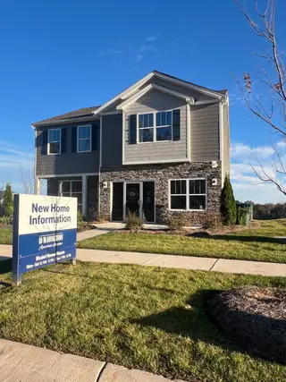 Street view A beautiful stone-accented home at Calvin Creek by D.R. Horton, featuring lush landscaping in Troutman, NC.