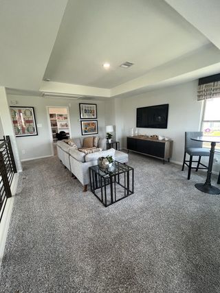 A cozy living room with plush carpet, modern decor, a sectional sofa, and wall-mounted TV offering a relaxed ambiance.