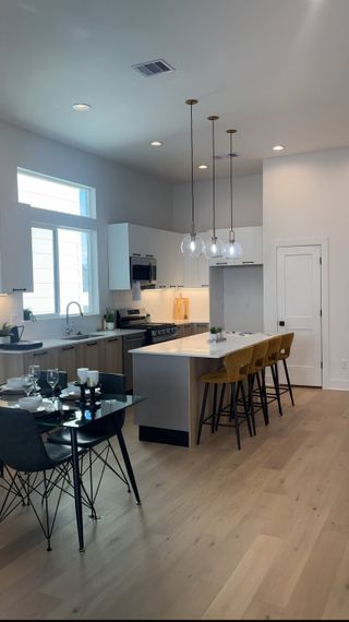 A modern kitchen with sleek white cabinets, pendant lighting, and a spacious island with seating.
