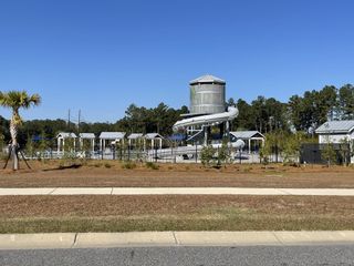 A vibrant community pool with a water slide set amid lush greenery in Pine Hills at Cane Bay by D.R. Horton (Summerville, SC).