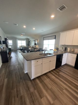 Model Home A stylish kitchen featuring a large island, black appliances, and granite countertops blending function with elegance.