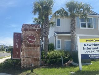 A charming home with palm trees and brick signage in The Landing by D.R. Horton (Middleburg, FL).