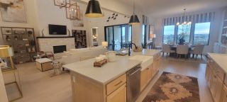 An elegant open-concept living area with modern kitchen, cozy fireplace, and chic dining space with large windows.