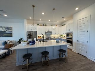 A spacious kitchen with white cabinetry, pendant lights, and a large island with seating.