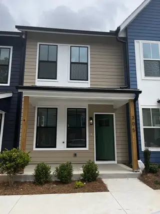 Street view A modern townhome with a green door and sleek siding in Avenue at Oakland City by Intown Builders, LLC (Atlanta, GA).