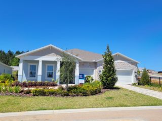 A stunning model home with stone accents, elegant columns, and beautifully landscaped surroundings in Del Webb Minneola by Del Webb (Minneola, FL).