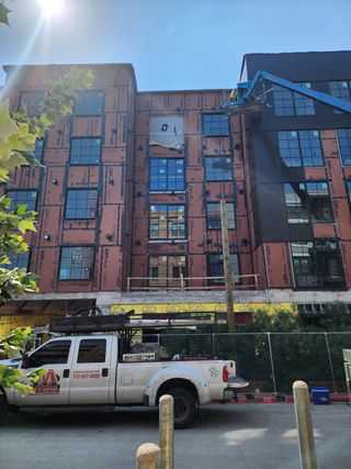 A modern apartment building taking shape at Congress Lofts Saint Elmo by Intracorp (Austin, TX), nearing completion with large windows.