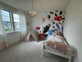 A charming kids' room with playful wall art, a cozy bed, and a small tent, filled with natural light and soft decor.