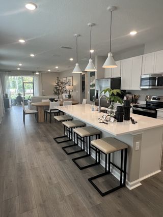 A contemporary kitchen with sleek white cabinets, pendant lighting, and a spacious island with modern barstools.