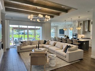 Elegant open-plan living area with a comfy sectional, modern lighting, and a spacious kitchen with island seating.