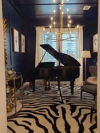 A sophisticated music room featuring a grand piano, bold zebra rug, and modern chandelier for a striking ambiance.