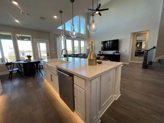 A spacious open-concept living area with large windows, a sleek kitchen island, modern lighting, and cozy dining space.