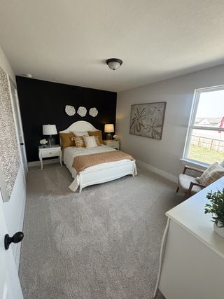 A comfortable and beautifully styled bedroom with a black accent wall, a white bed frame, and mustard-colored bedding.