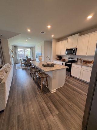 A modern kitchen with sleek white cabinets, granite countertops, and a spacious island, opening to a bright dining area.