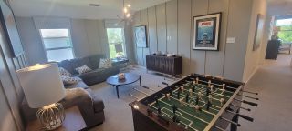 A cozy rec room with a plush sofa, foosball table, and chic décor, accentuated with classic movie posters.