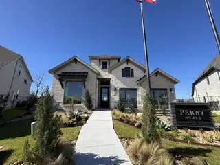 A beautiful stone-clad home with manicured landscaping in Legacy at Lake Dunlap 50' by Perry Homes (New Braunfels, TX).