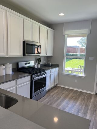 Model Home A modern kitchen with sleek cabinets, stainless steel appliances, and wood flooring illuminated by natural light.