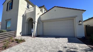 A modern stucco home with arched entry and paved driveway in Black Rock at Verrado by Woodside Homes (Buckeye, AZ).