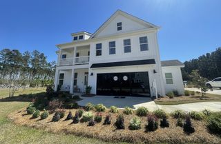 Charming white home with a cozy porch and landscaped yard in Lochton by Mungo Homes, Summerville, SC.