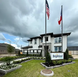 Street view A modern two-story home with sleek lines and landscaped gardens in Beamer Villas by Brightland Homes (Friendswood, TX).