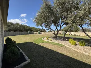 Model Home A spacious backyard with mature trees and manicured landscaping in Wolf Ranch 56' by Perry Homes (Georgetown, TX).