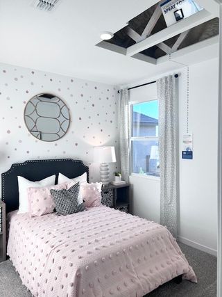 Street view A cozy bedroom featuring a polka dot accent wall, decorative mirror, and stylish bedding with soft pastel tones.