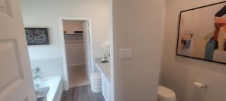 Model Home A modern bathroom featuring a bathtub, granite countertop, and decorative art.