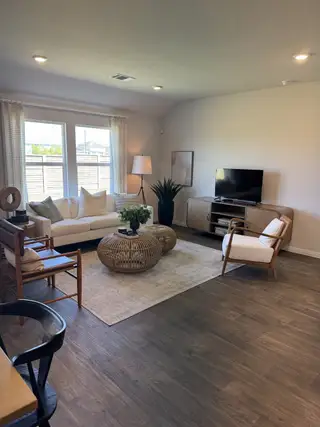 A cozy living room with wood flooring, modern wicker furniture, and a bright, airy atmosphere.