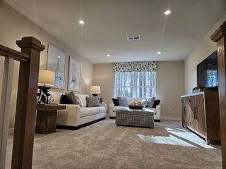 A cozy living room featuring plush sofas, elegant lamps, and a large window with forest views, perfect for relaxation.