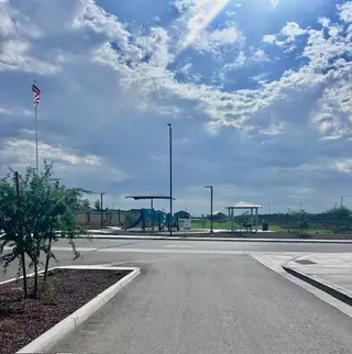 A sunny community park with a playground in Monroe Ranch by K. Hovnanian® Homes (Buckeye, AZ).