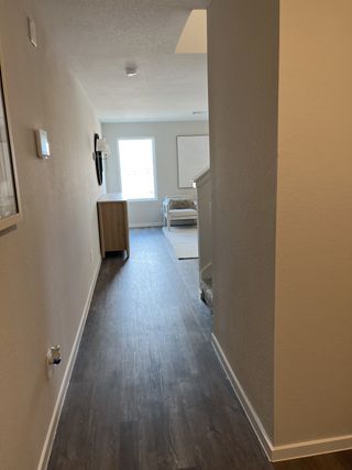 A bright hallway with wooden flooring, leading to a cozy sitting area illuminated by natural light.