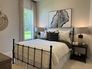 Model Home A cozy bedroom with a metal bed frame, layered bedding, abstract art, and soft lighting.