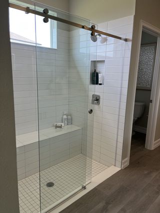 A sleek, modern shower with a built-in bench and sliding glass door, featuring white subway tiles and a stylish niche.