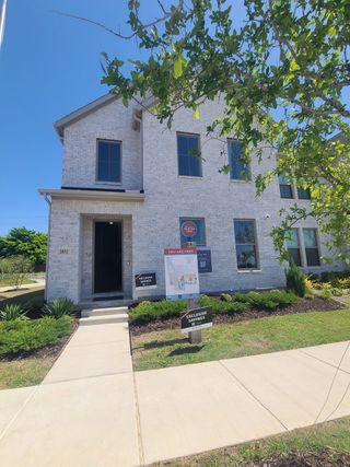 A charming white brick home with lush landscaping in Painted Tree - Village District by CB JENI Homes (McKinney, TX).