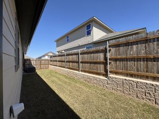 A charming fenced backyard with a wooden fence and siding in Saddle Creek Ranch by HistoryMaker Homes (Cibolo, TX).