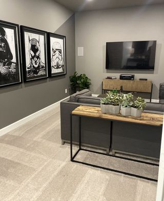 A cozy media room with plush carpeting, a large TV, and striking black-and-white framed artwork.