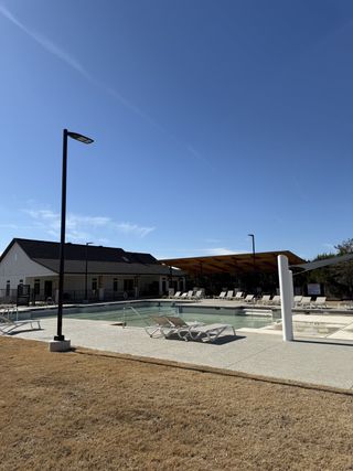 A modern poolside view with sun loungers in Bar W Ranch by D.R. Horton (Leander, TX).