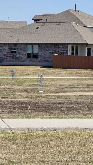 A residential community featuring a disc golf course, a modern clubhouse, a landscaped entrance sign, and well-designed homes.