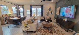 Model Home A cozy open-concept living and dining area with stylish decor, large windows, and a sleek accent wall with a mounted TV.