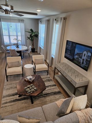 Model Home A cozy living space with a stylish hexagonal coffee table, comfy chairs, and natural light from large windows.