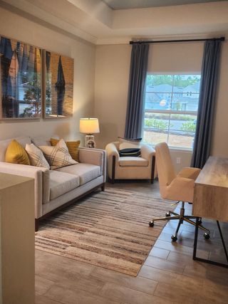 A cozy living space with a plush sofa, stylish artwork, a modern desk, and warm lighting.
